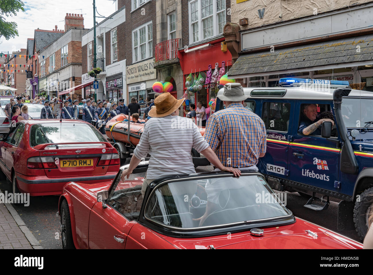 Un couple regarder le défilé de carnaval Prestatyn passent de leur voiture de sport à toit ouvert Banque D'Images