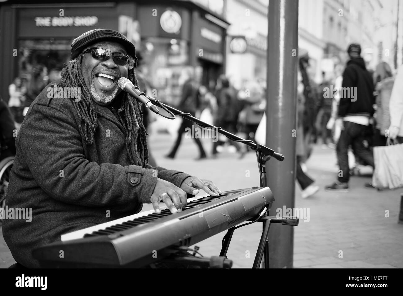 Un homme avec des dreadlocks afro et lunettes joue du clavier dans la rue d'une ville britannique. Banque D'Images