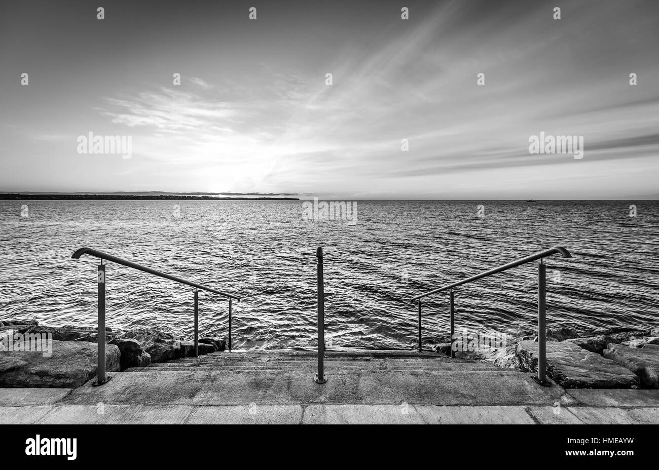 Étapes sur une plage avec le coucher du soleil sur l'océan mer. Photo de paysage du lever ou du coucher du soleil sur une plage naturelle à Piran, Slovénie. Banque D'Images