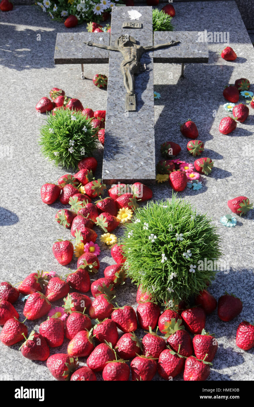 Crucifix et fausses fraises sur une pierre tombale. Banque D'Images