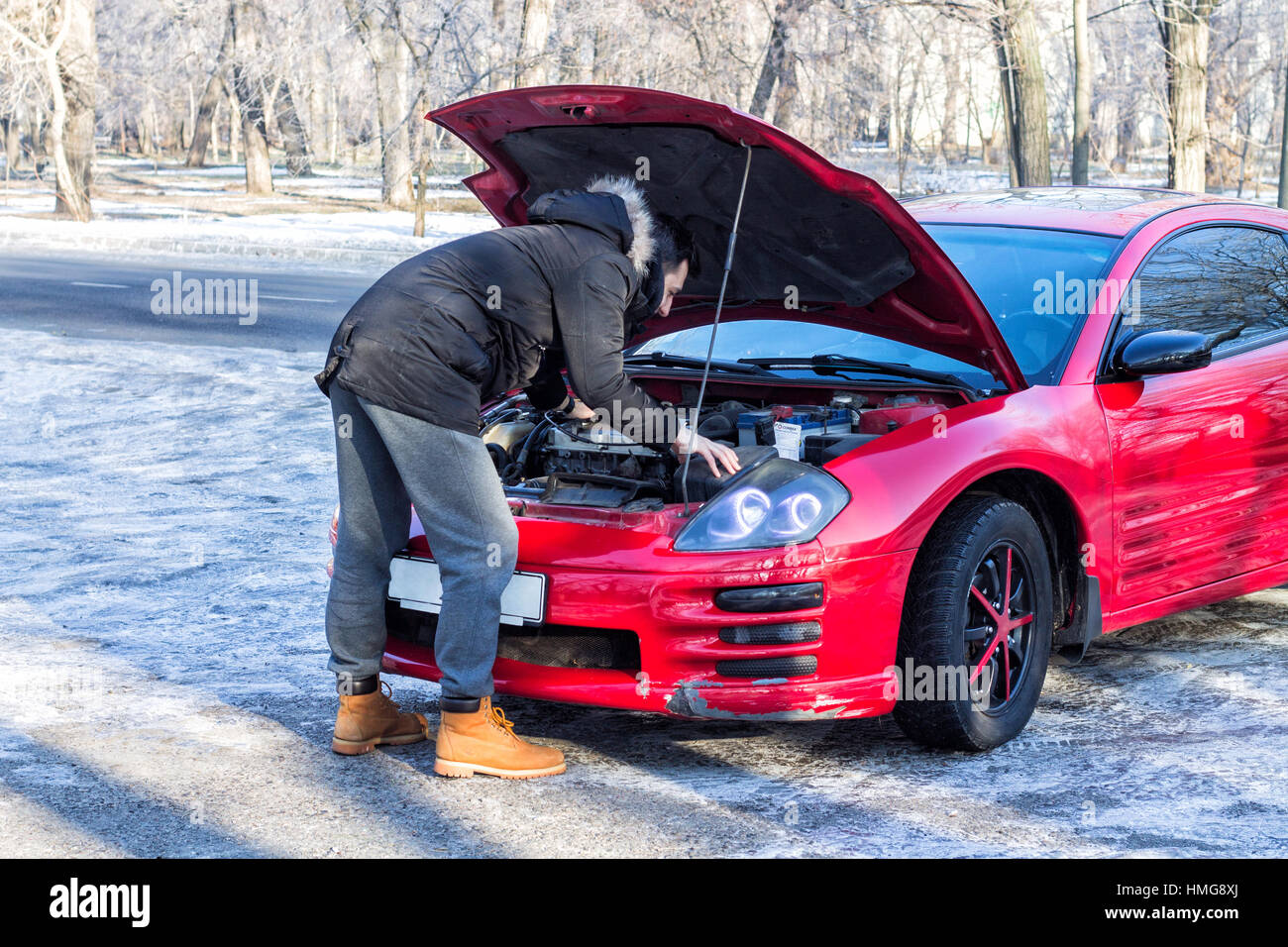 L'homme en difficulté avec sa voiture cassée .Il est en train de regarder sous le capot moteur. La saison d'hiver Banque D'Images