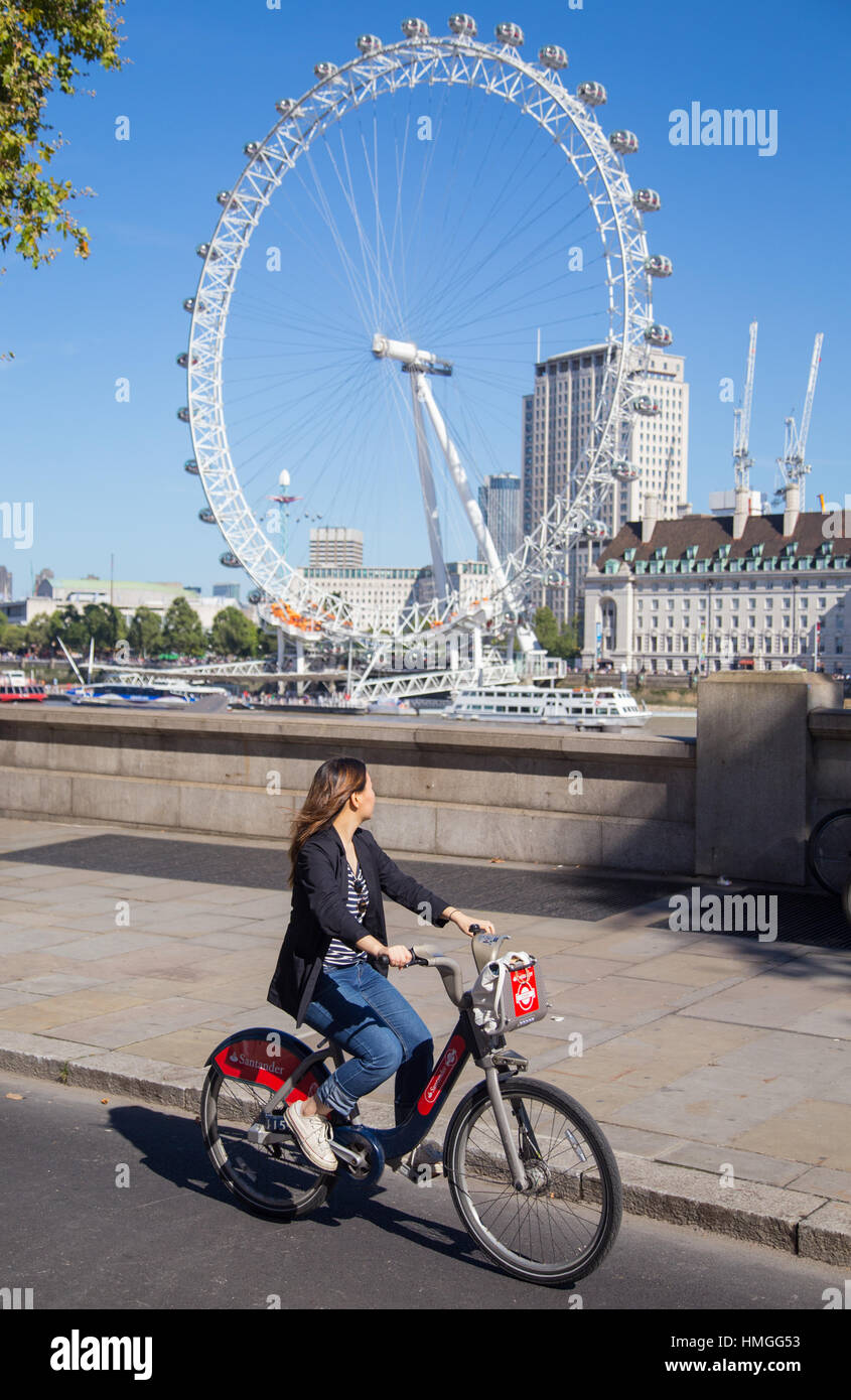 Jeune femme équitation cycliste vélo voitures Santander sur autoroute cycle est-ouest avec London Eye en arrière-plan sur un week-end d'été ensoleillé à Londres Banque D'Images