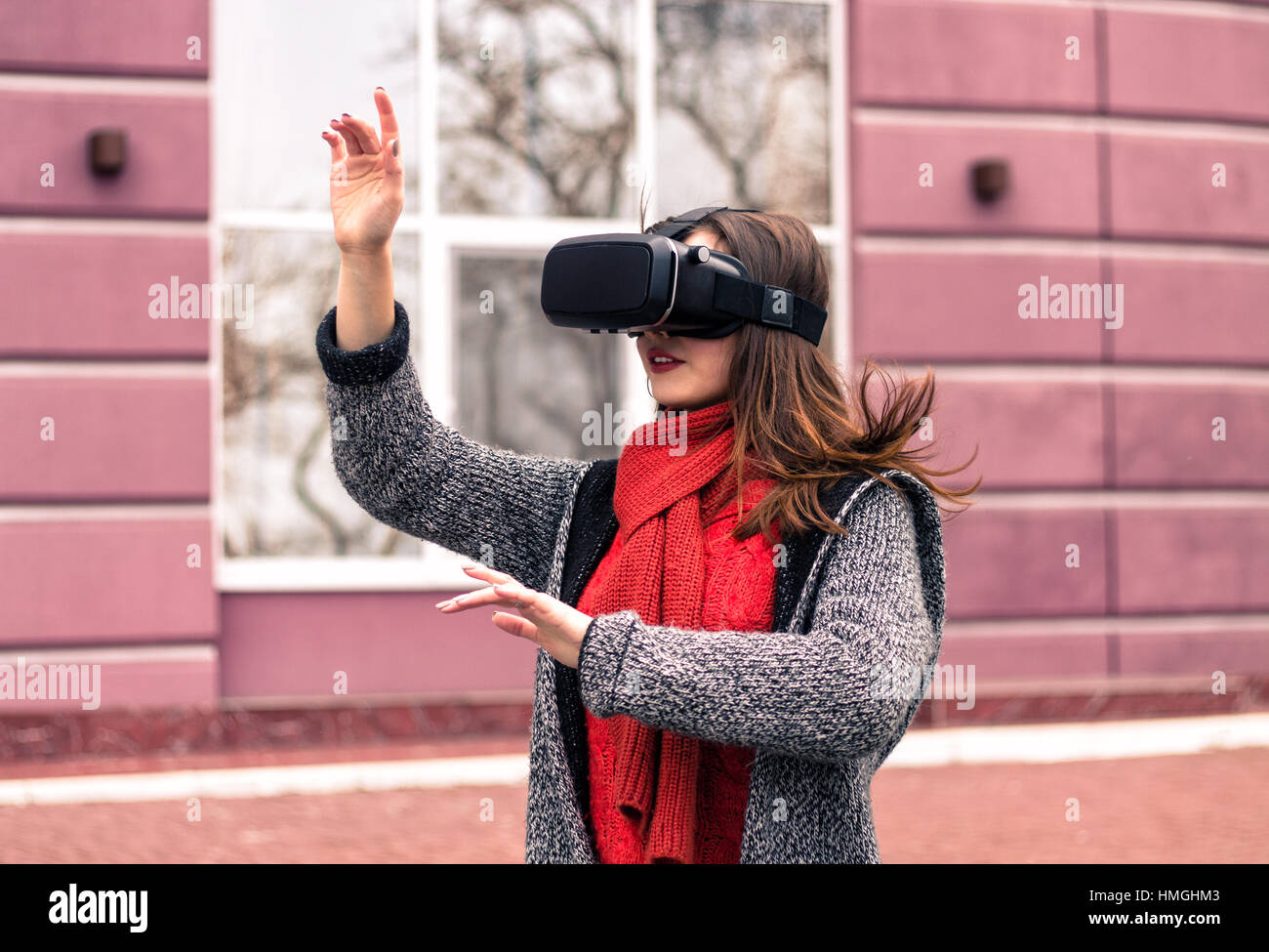 Casque de réalité virtuelle, lunettes, lunettes VR VR - belle jeune fille avec casque de réalité virtuelle ou des lunettes 3d poser dans la rue intéressé par Banque D'Images
