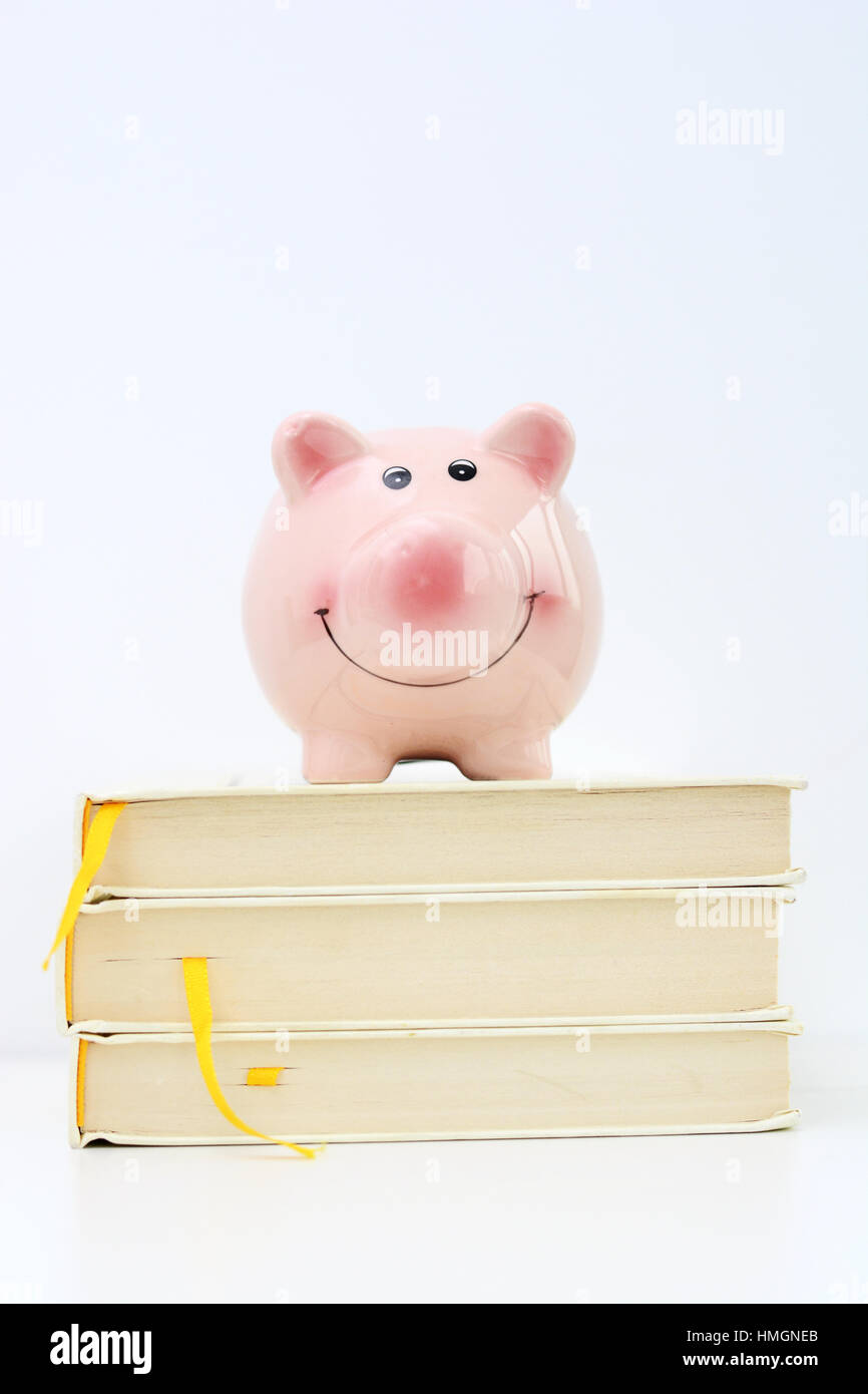 Tirelire en haut de pile de livres suggérant l'épargne pour college Banque D'Images