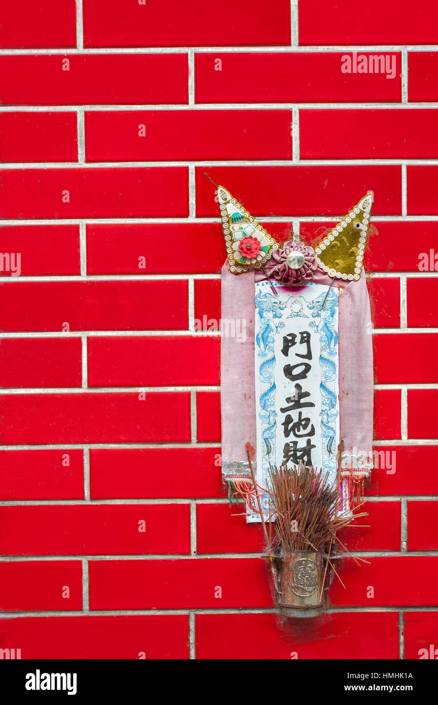 Petit sanctuaire de la terre Dieu Tu Di monté sur un mur carrelé rouge à Hong Kong Banque D'Images
