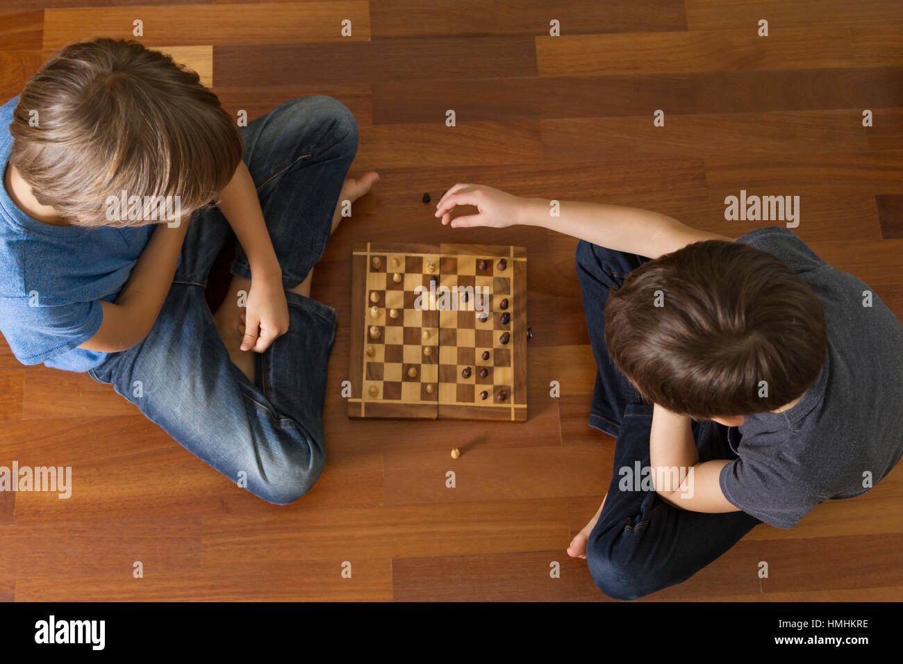 Enfants jouant aux échecs assis sur un plancher en bois. Vue d'en haut. Jeu, l'éducation, de vie, concept de loisirs Banque D'Images