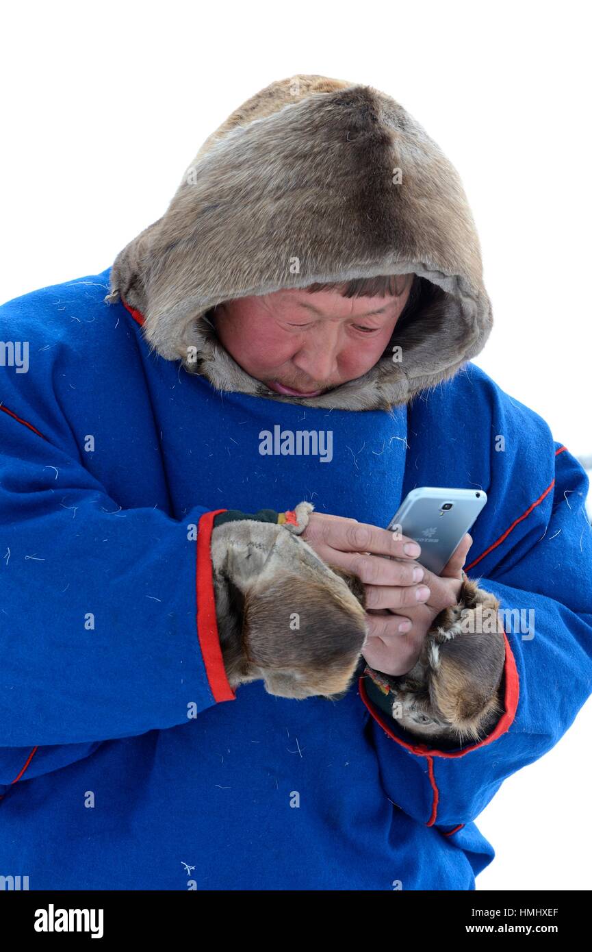 Gardien de rennes nenets dans son traditionnel malitsa / manteau en peau de  renne en regardant son smartphone, yar-vente, district du nord-ouest de  Yamal, Sibérie, Russie Photo Stock - Alamy