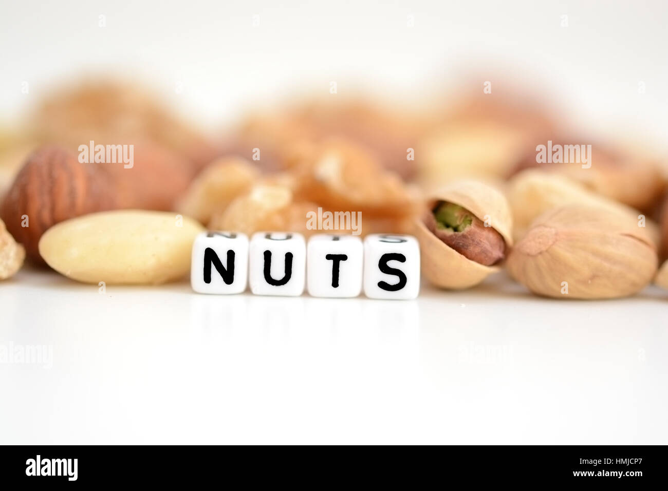 Matières mélangées et le mot "Nuts" écrit par Sol carrelé lettre beads étendre sur une table blanche Banque D'Images