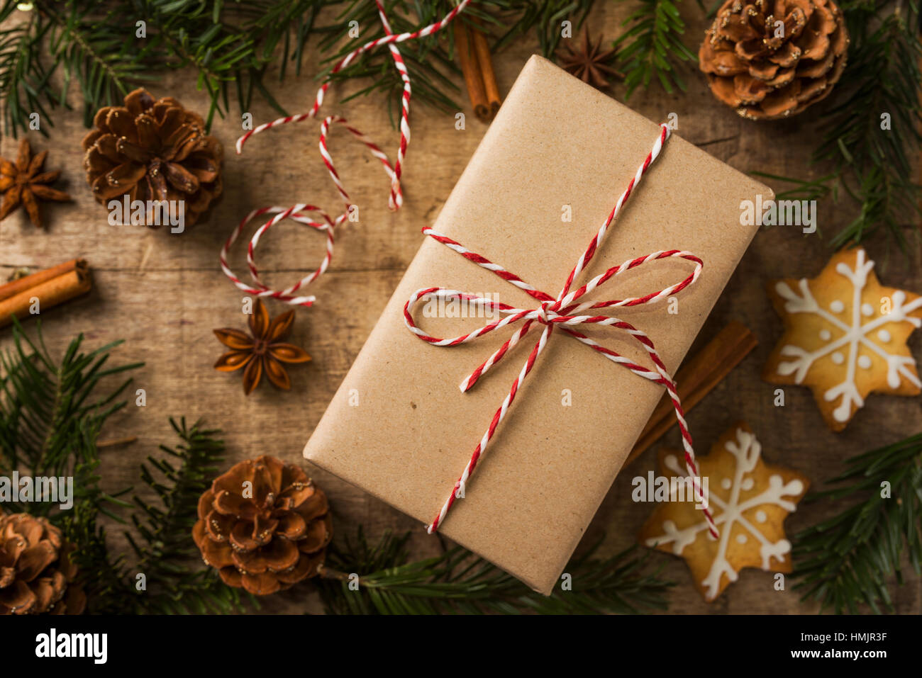 Cadeau de Noël enveloppé dans du papier kraft et entouré de décoration. Photo tonique pour des couleurs chaudes Banque D'Images