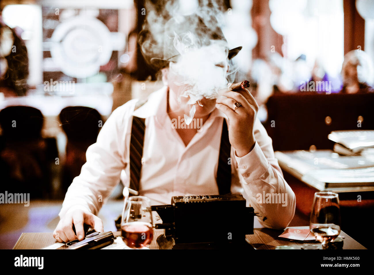 Séance mafieux et fumer un cigare à travers la fumée Banque D'Images