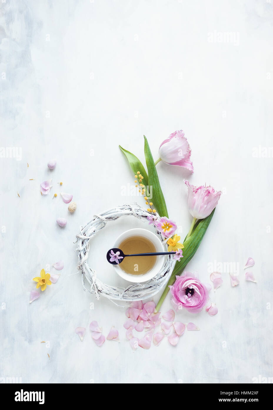 Still life style télévision laïcs de tulipes et autres fleurs de printemps avec couronne blanche tasse et mini-oeufs sur fond gris et blanc Banque D'Images
