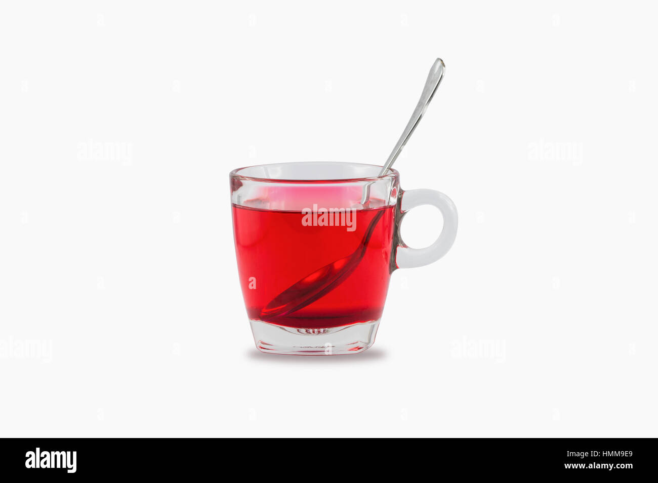 Poison rouge artificiel, à base de sirop sucré et de l'eau dans le verre tasse avec cuillère à café en acier inoxydable isolé sur fond blanc. Banque D'Images