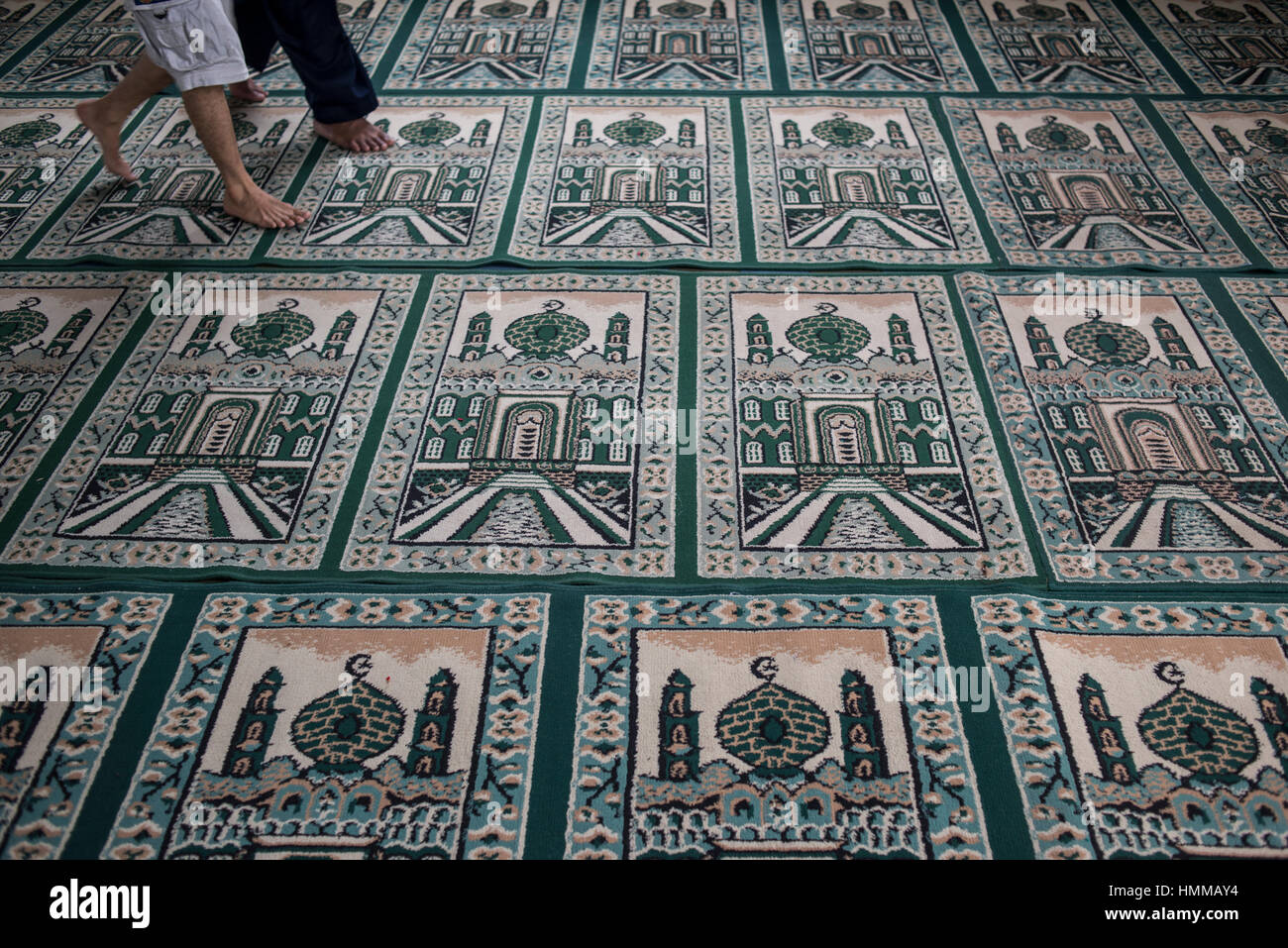 Les gens qui marchent sur les tapis de prière musulmane haut de l'intérieur de la Grande Mosquée de Medan, Sumatra, Indonésie. Banque D'Images