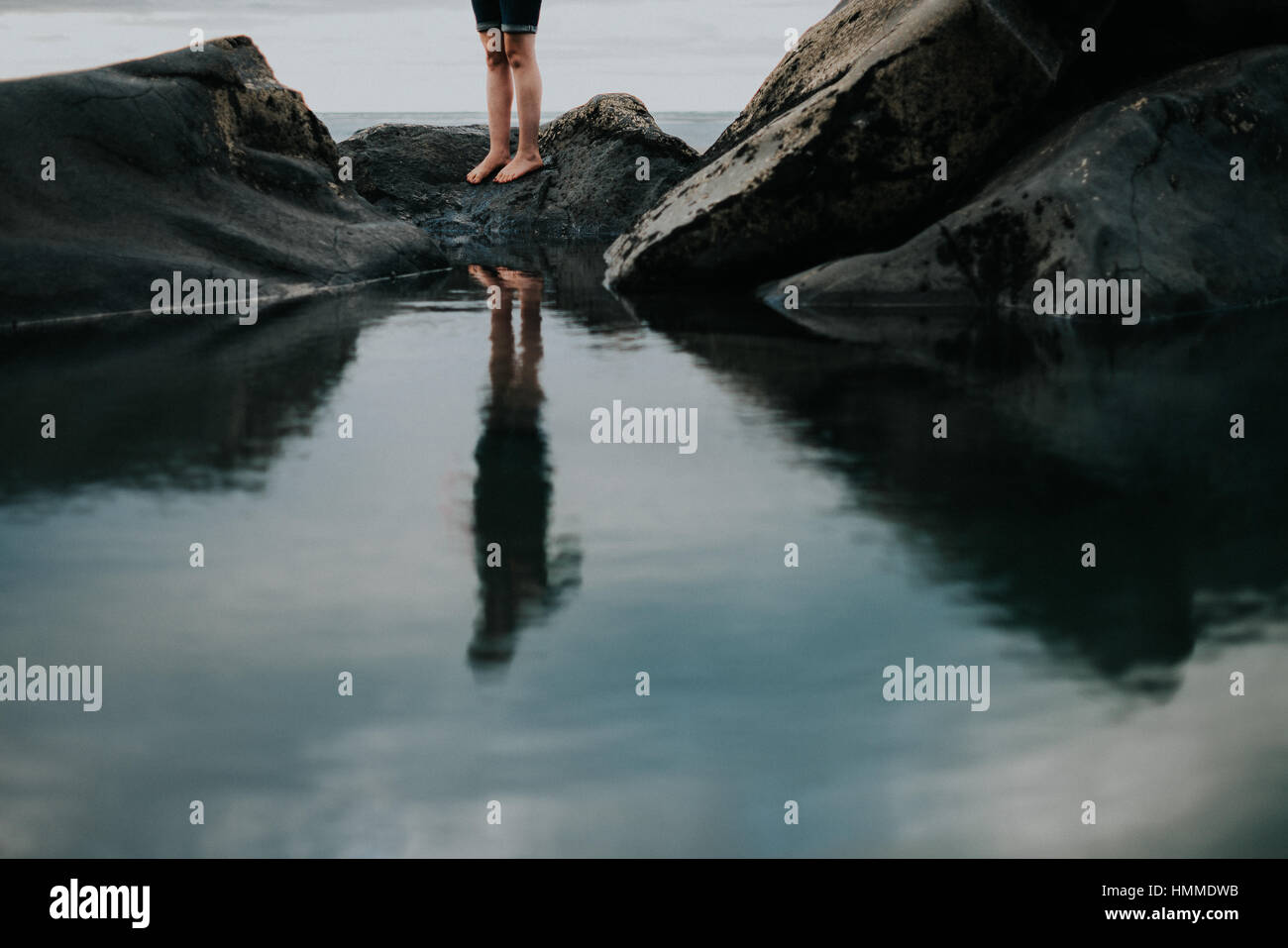 Un reflet dans l'eau d'une personne debout sur certaines pierres. Banque D'Images