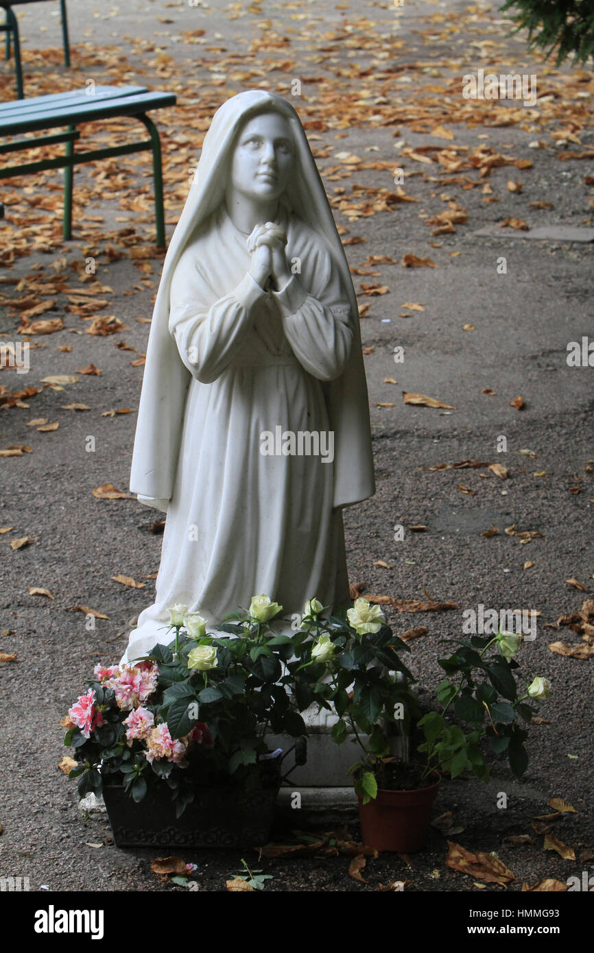 Sculpture de Bernadette Soubirous priant devant la statuette de la Vierge-Marie. La Grotte de Lourdes. Couvent Saint-Gildard. Nevers. La France. Banque D'Images
