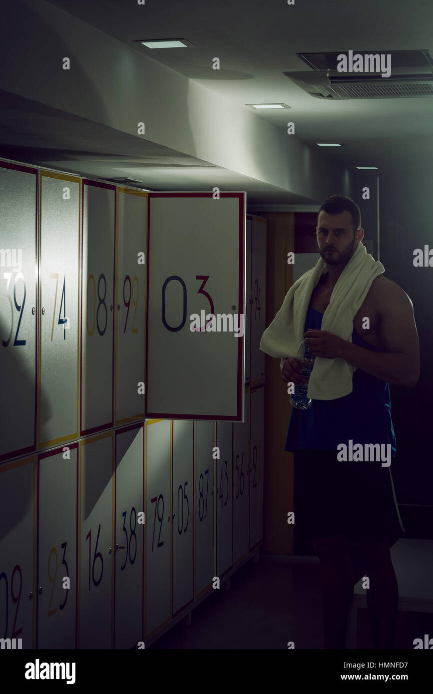 Mettre en place des jeunes adultes homme debout dans vestiaire et casier ouverture porte. Banque D'Images