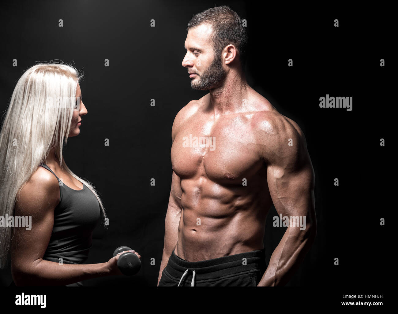 Young couple fitness adultes dans la vingtaine travaillant ensemble à faire de biceps avec haltères. Isolées. Banque D'Images