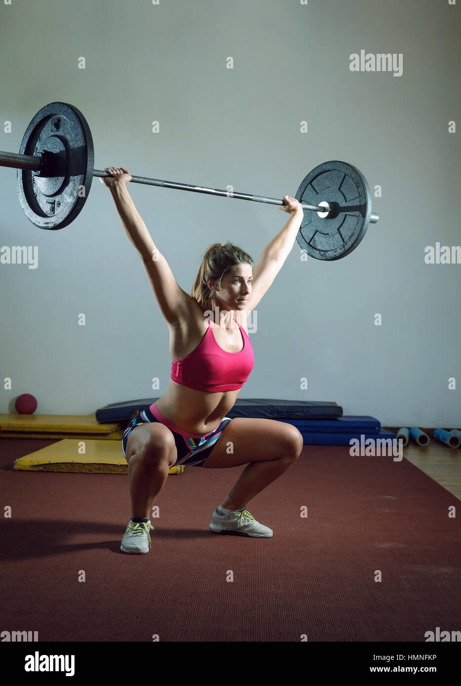 Les jeunes adultes girl doing squats lourds en sport avec barbell Banque D'Images