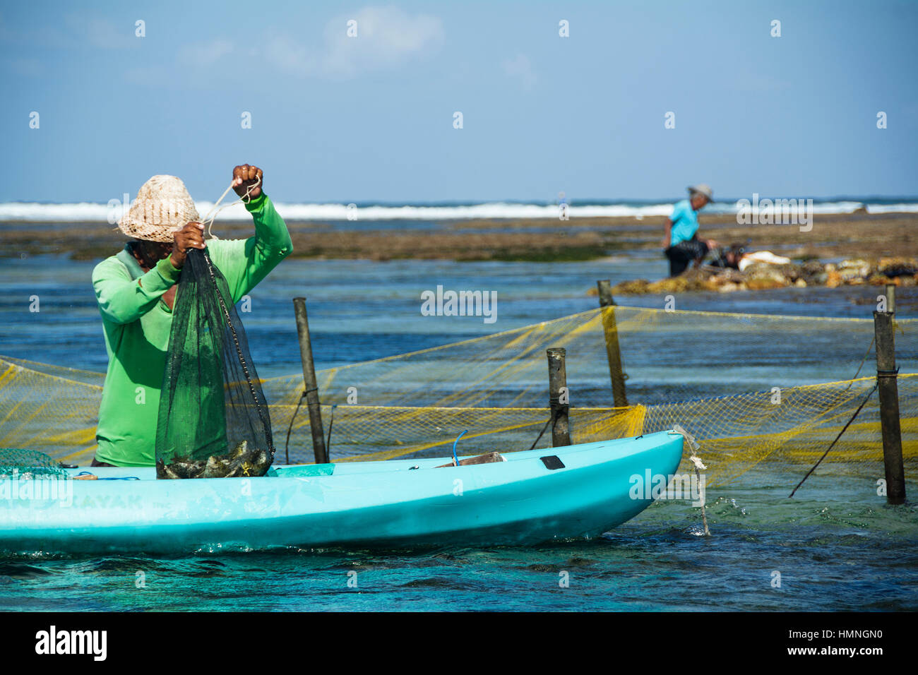 Deux pêcheurs recueillir leur pêche sur la plage de Seminyak, Bali Banque D'Images