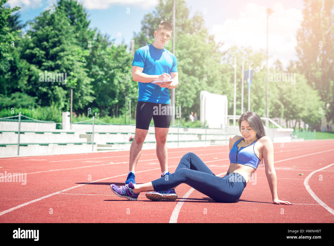 Remise en forme des jeunes adultes woman posing outdoors at piste d'athlétisme avec son entraîneur personnel. Banque D'Images