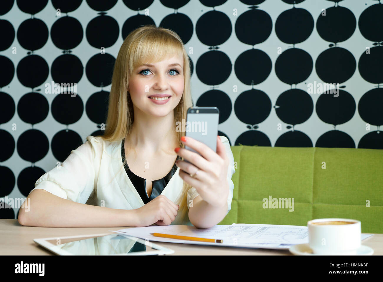 Girl sitting in cafe est titulaire d'un téléphone mobile Banque D'Images