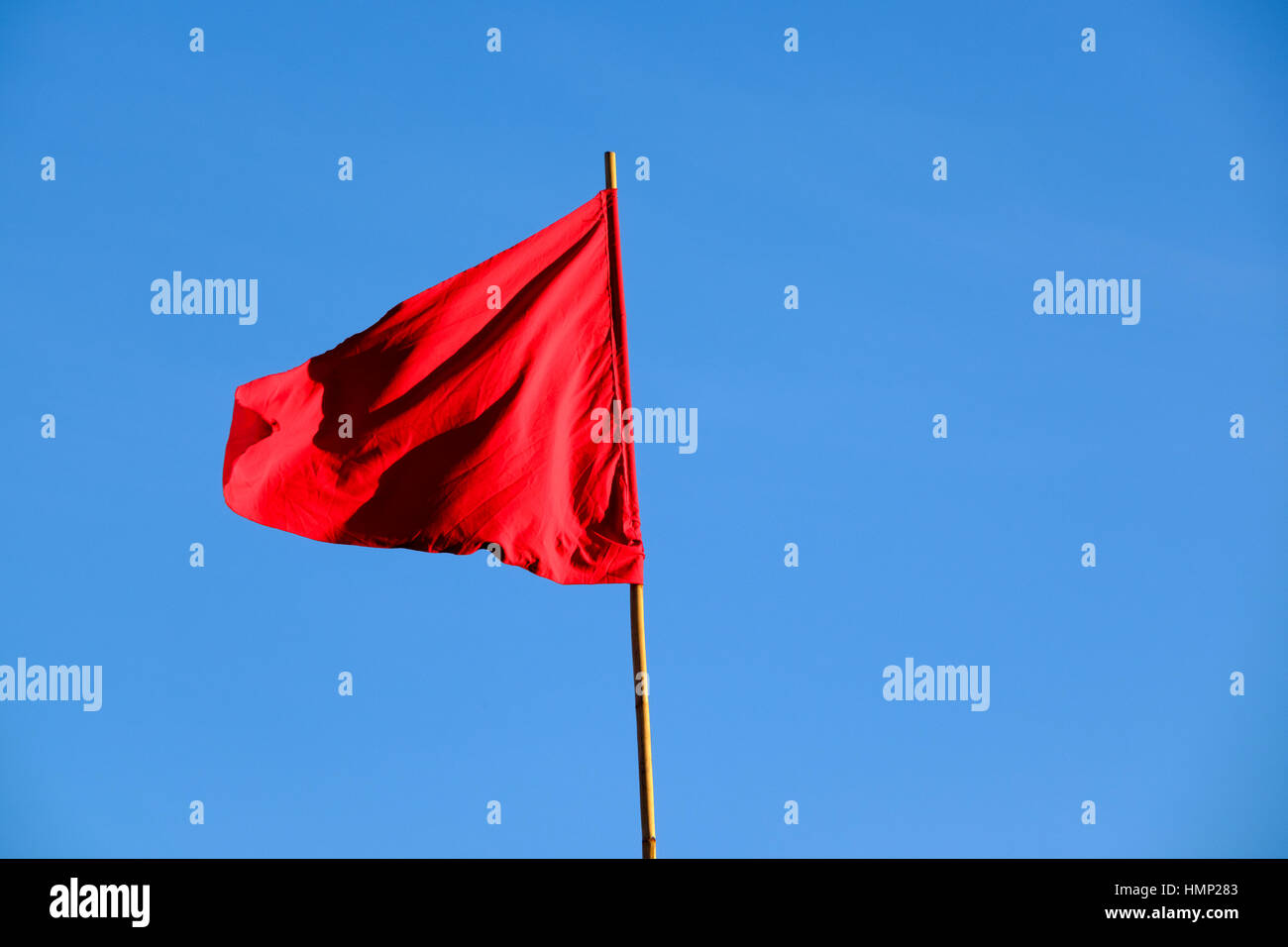 Drapeau triangulaire rouge contre un ciel bleu en fin d'après-midi Banque D'Images