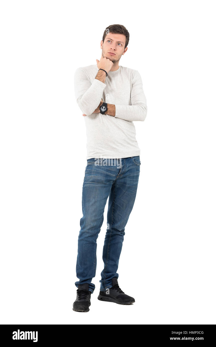 Thoughtful casual man inquiète avec la main sous le menton en haut. La pleine longueur du corps portrait studio isolated over white background. Banque D'Images