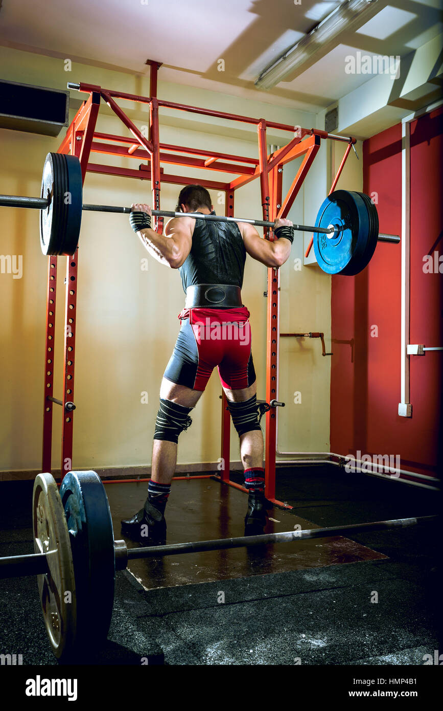 Jeune homme s'accroupit dans l'adolescence de sport à l'club. Banque D'Images
