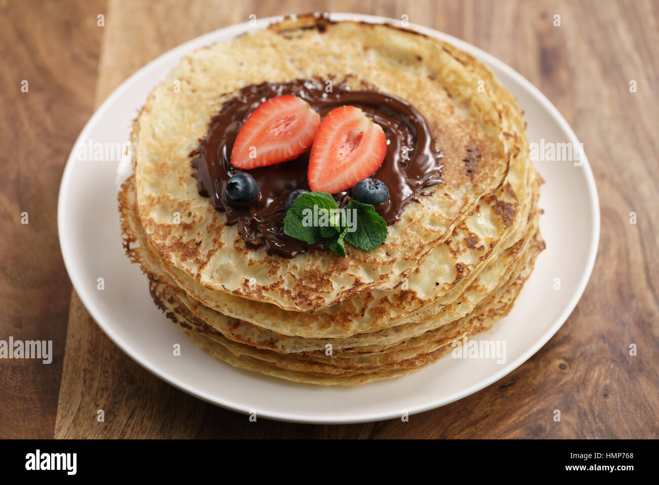 Blinis frais ou des crêpes avec du chocolat noir fondu et les baies Banque D'Images