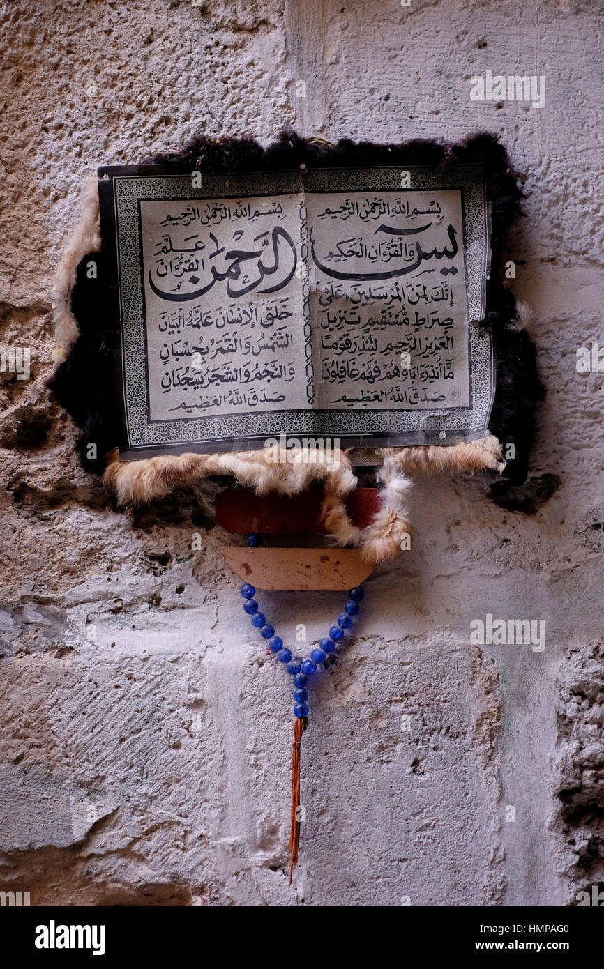 Des versets du Coran islamique religieuse ou de Coran en arabe sur un parchemin de chèvre pendu dans le mur dans une ruelle au quartier musulman, vieille ville Jérusalem Israël Banque D'Images