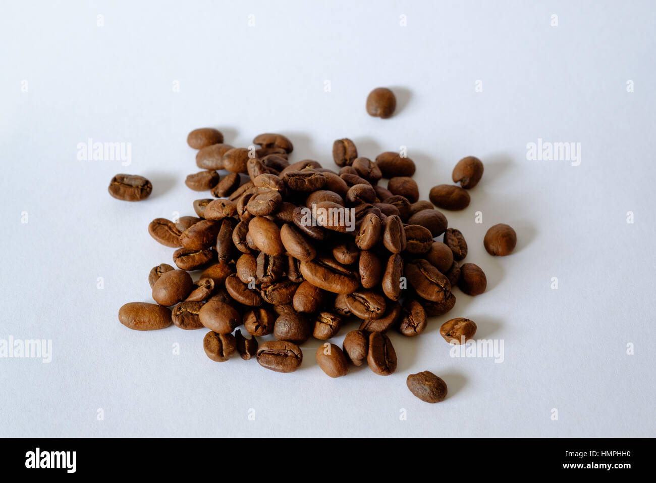 Petit tas de grains de café torréfiés sur fond blanc Banque D'Images