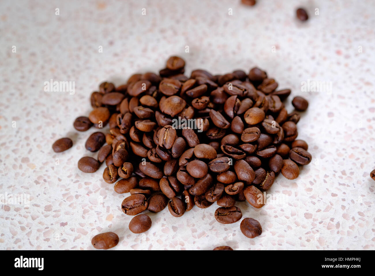 Petit tas de grains de café torréfiés sur un comptoir moucheté Banque D'Images
