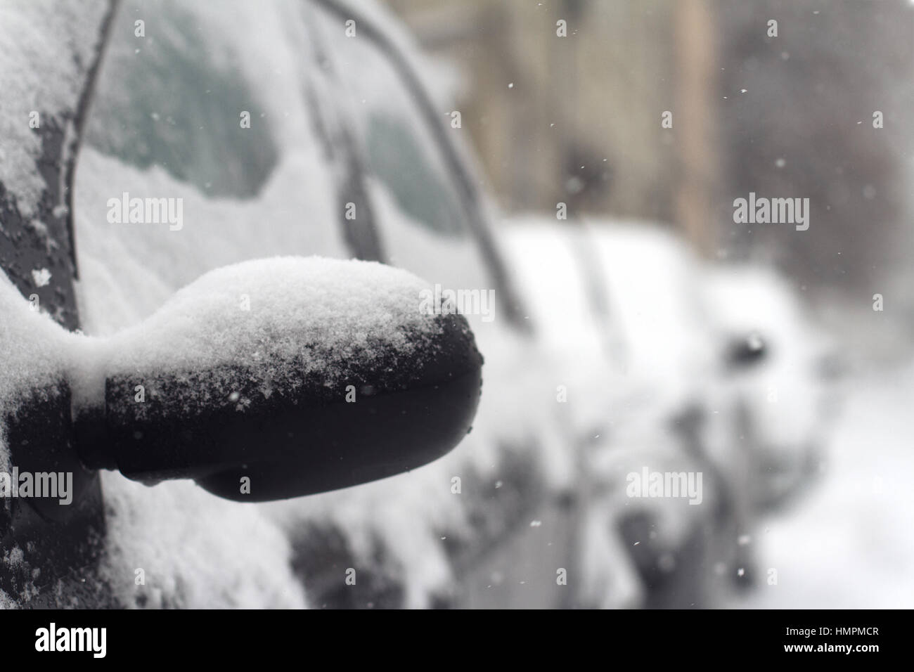 Close up of black car miroir arrière de côté avec la neige qui tombe en hiver sur une rue de la ville Banque D'Images