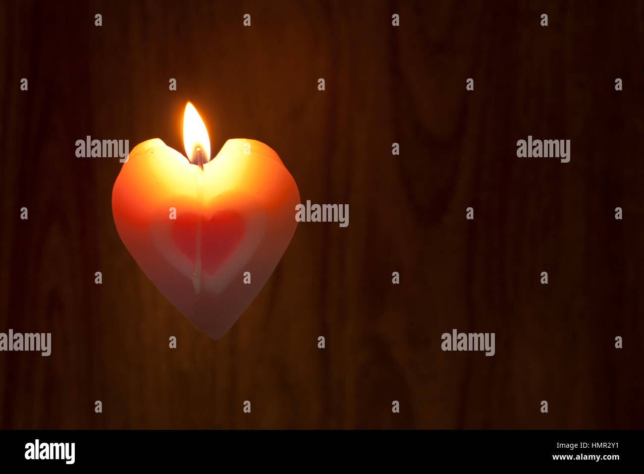 Forme coeur couleur rose bougies étaient allumées sur fond de bois. Symbole d'amour pour la Saint Valentin de concept. Banque D'Images