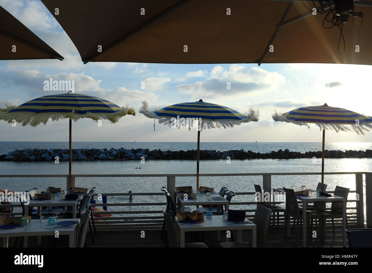 Bar sur la plage au coucher du soleil - restaurant en bord de mer avec vue sur mer à l'heure d'or juste avant le coucher du soleil - Tables et parasols de plage - Marina di Pisa, Italie Banque D'Images