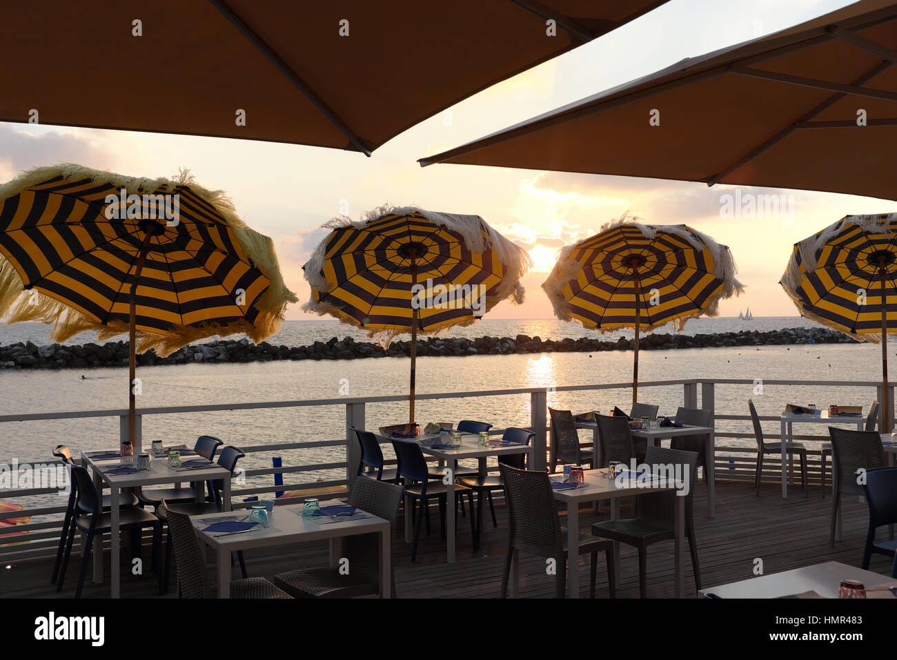 Bar sur la plage au coucher du soleil - restaurant en bord de mer avec vue sur mer à l'heure d'or juste avant le coucher du soleil - Tables et parasols de plage - Marina di Pisa, Italie Banque D'Images