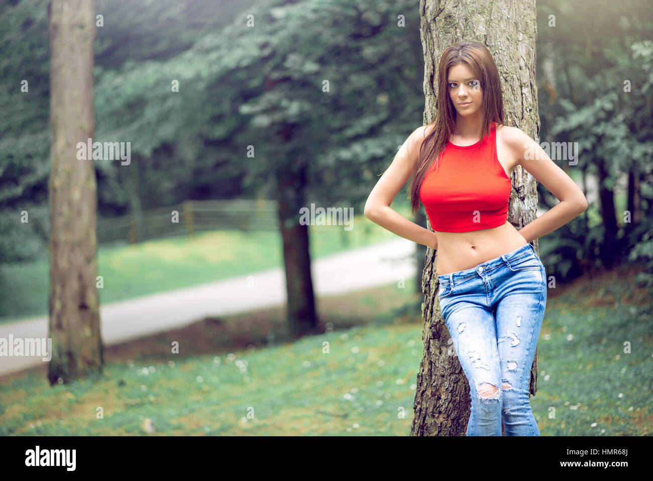 La mode des jeunes adultes woman posing braless en forêt de montagne naturel authentique emplacement. Porter du rouge top et jeans pantalons. La tonalité de l'image. Banque D'Images