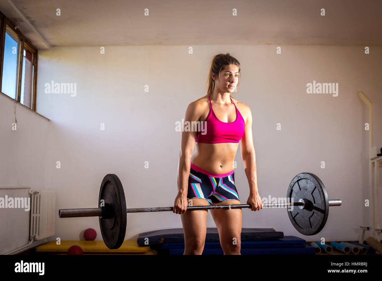 Jeune fille adultes faisant l'haltérophilie lourde au cours de sport exercice actif. Une volonté à toute épreuve. La tonalité de l'image. Banque D'Images