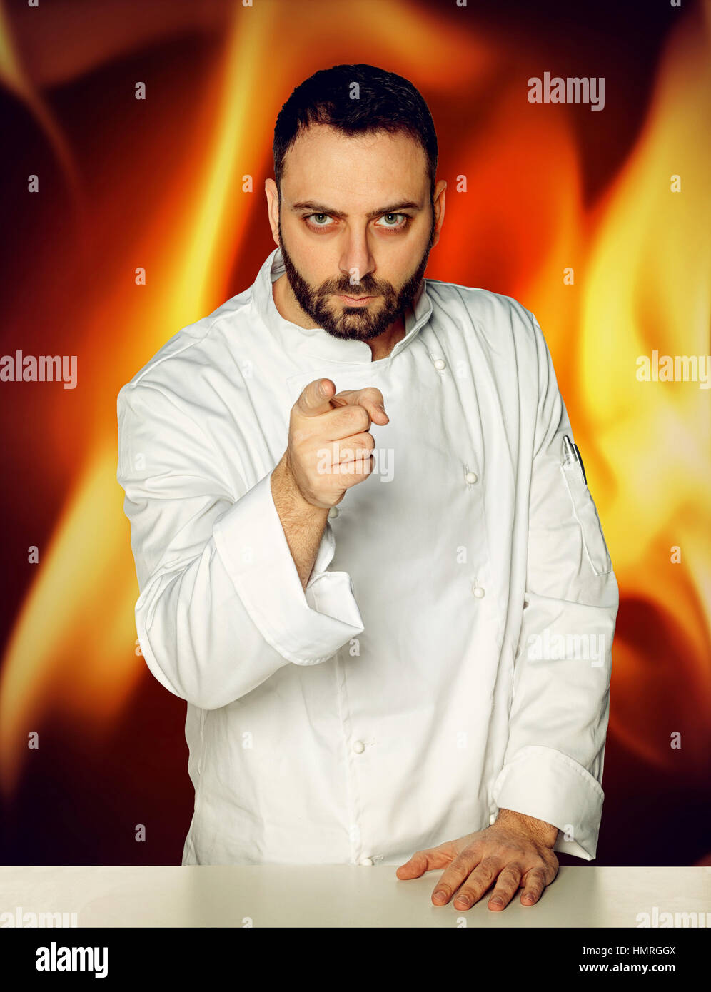 Jeune chef en uniforme blanc sur fond Fiery Banque D'Images