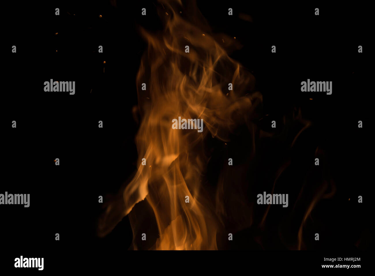 Flamme orange à la hausse dans l'obscurité, des braises et des étincelles voler autour d'elle Banque D'Images