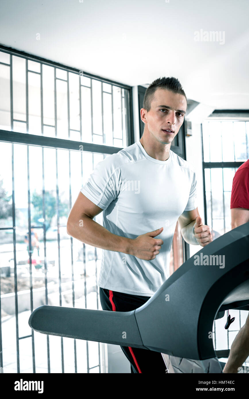 Les jeunes adultes fit homme qui court sur un tapis roulant dans une salle de sport Banque D'Images