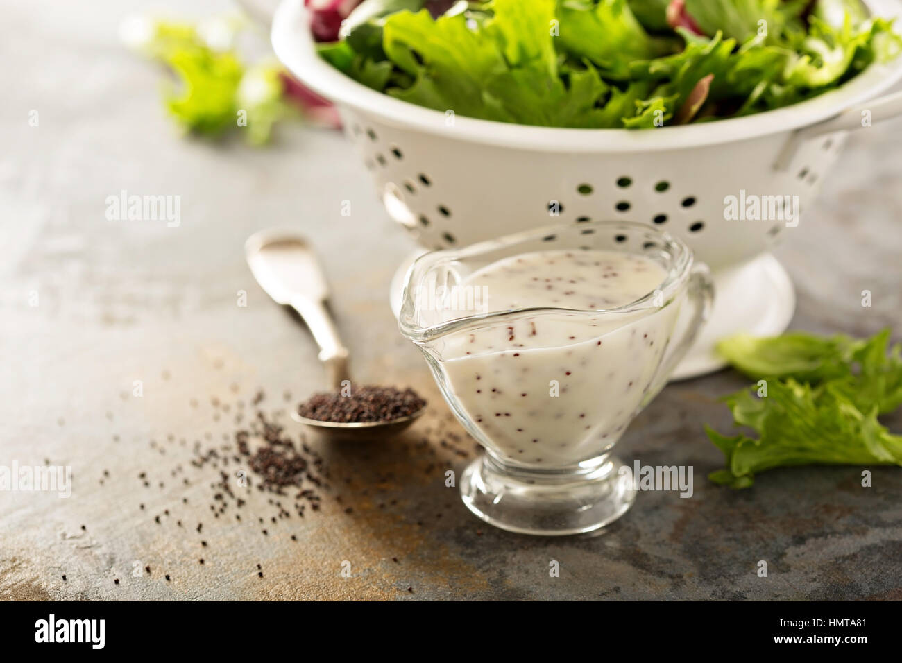 Les graines de pavot ou de sauce vinaigrette dans un plat en verre avec des feuilles de salade