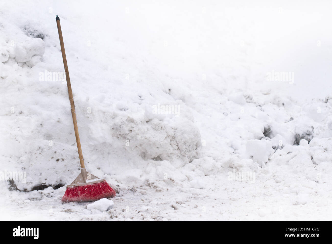 Vue avant de la maison rouge à balai en face de neige recueillie dans une pile en hiver Banque D'Images