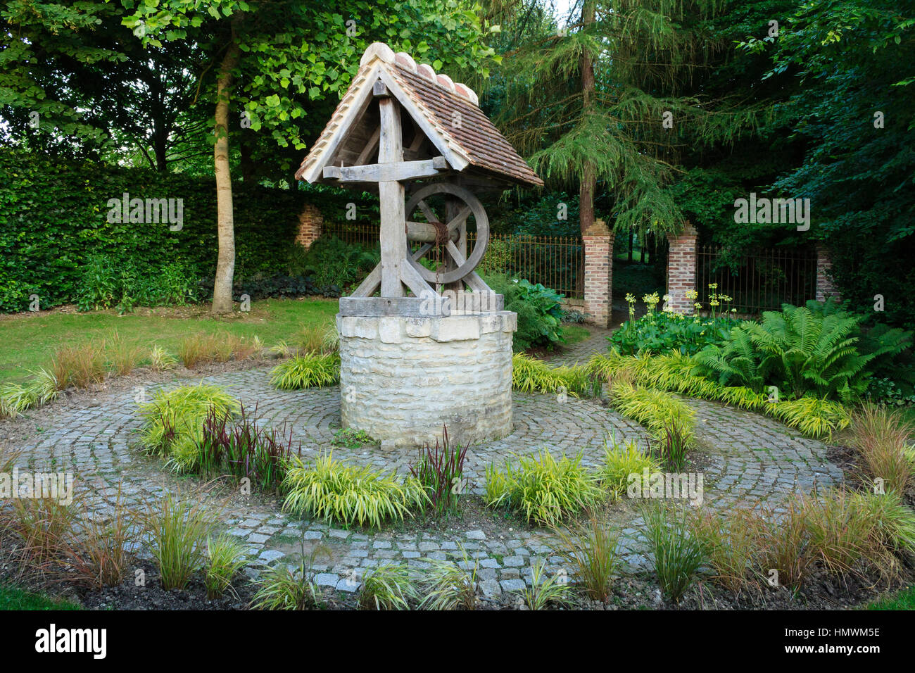 Jardins du pays d'Auge, Normandie, France : autour du puits, les graminées, les fougères et les primevères. Banque D'Images