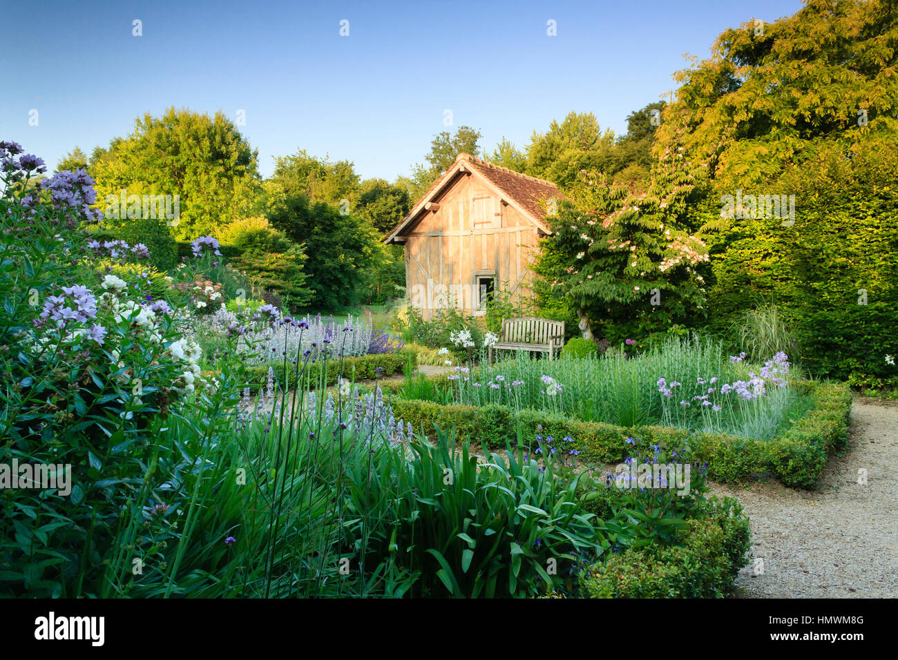 Jardins du pays d'Auge, ici jardin appelé 'le repos du jardinier' avec une grange et 4 carrés de boîtes et de vivaces Banque D'Images