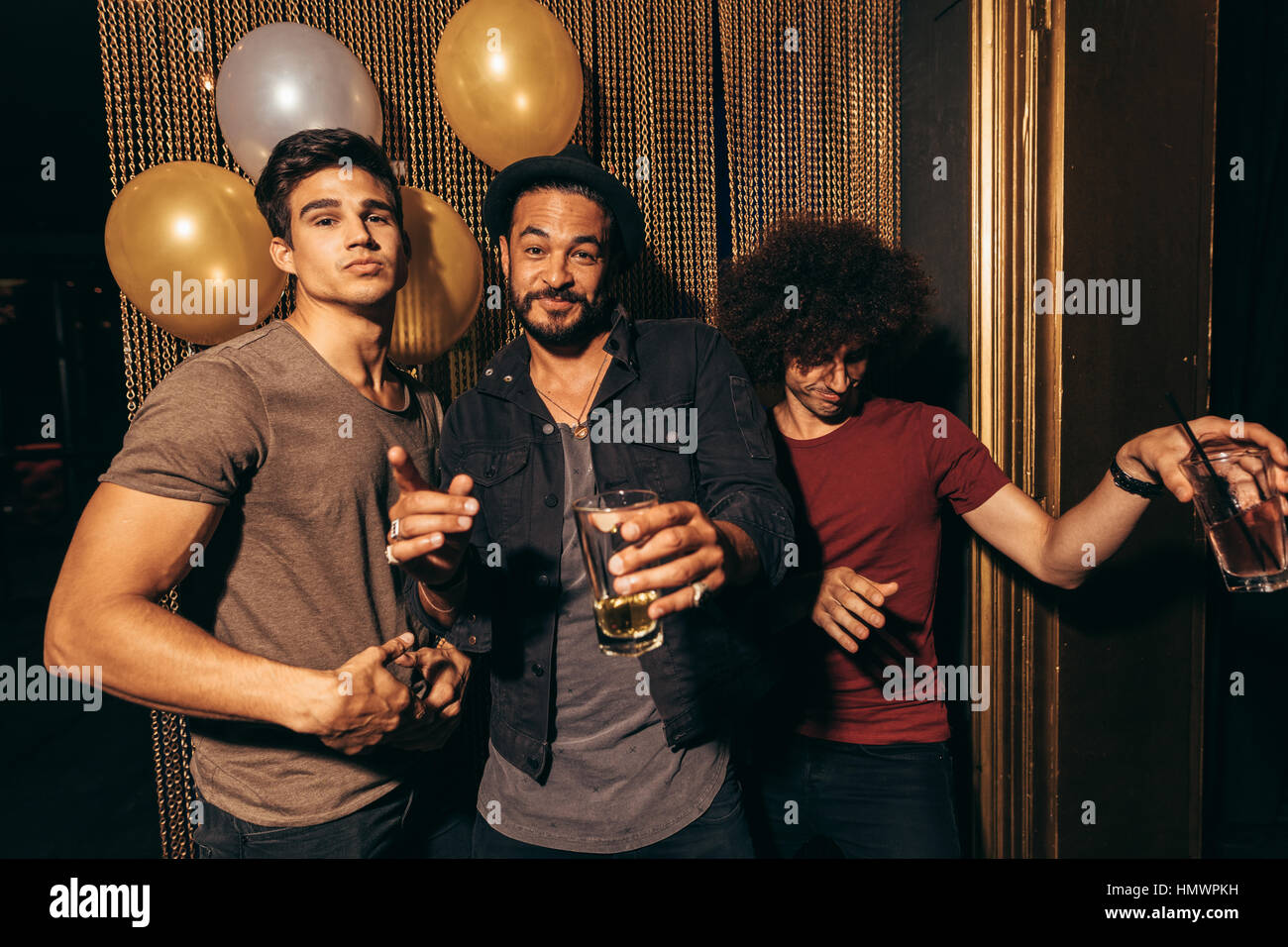 Portrait de trois jeunes hommes s'amuser à la discothèque. Groupe d'hommes au pub avec des boissons. Banque D'Images