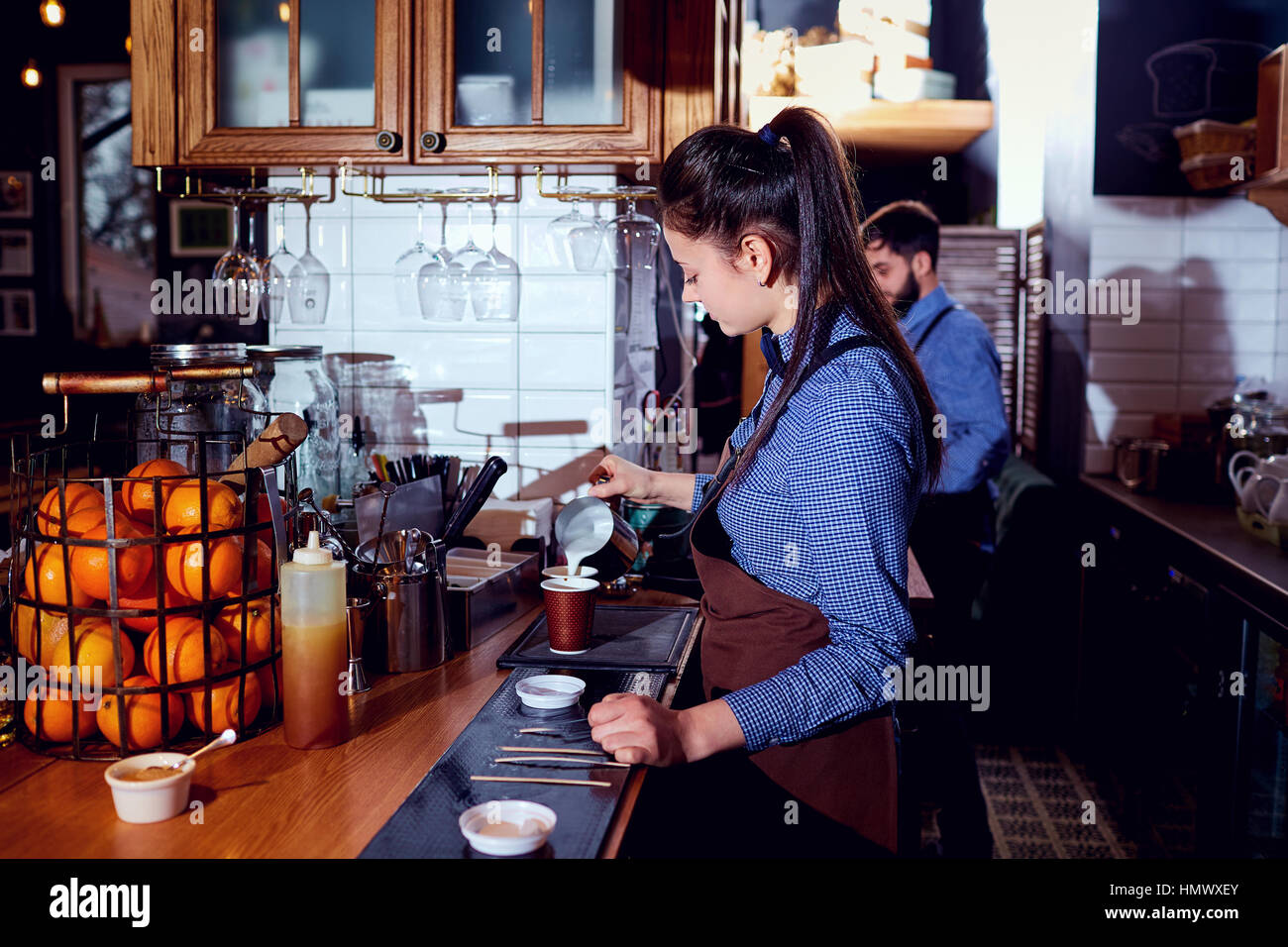 Le barman, barista, elle prépare du lait chaud au bar à café res Banque D'Images