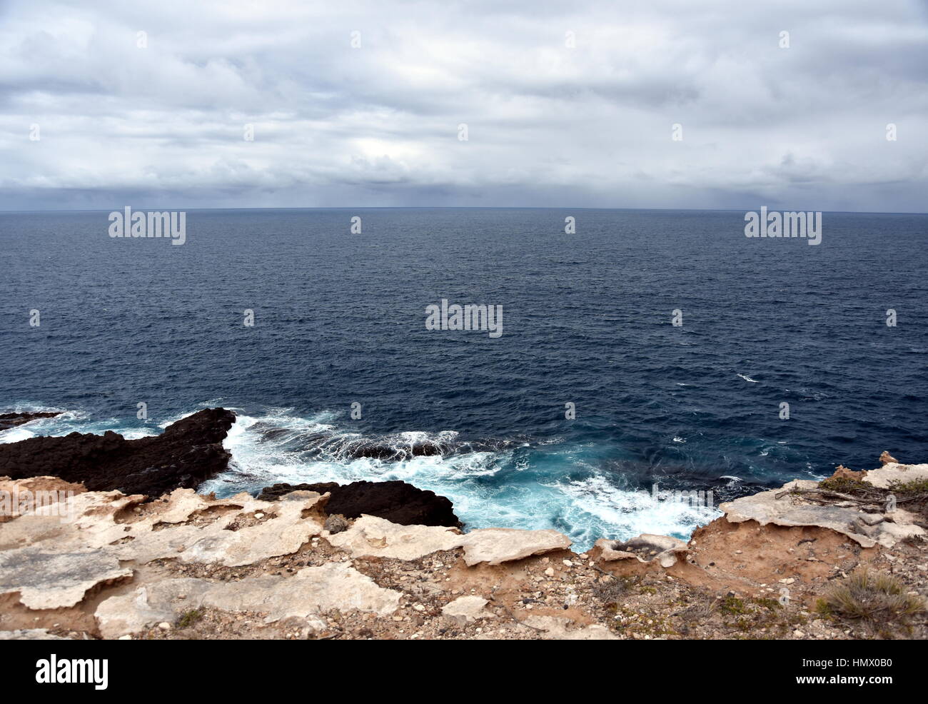 Mer jaillissante sur un jour nuageux. Vue horizontale de ciel couvert et de la mer. Cinquante nuances de bleu. Vagues se brisant sur les rochers de l'océan. Banque D'Images