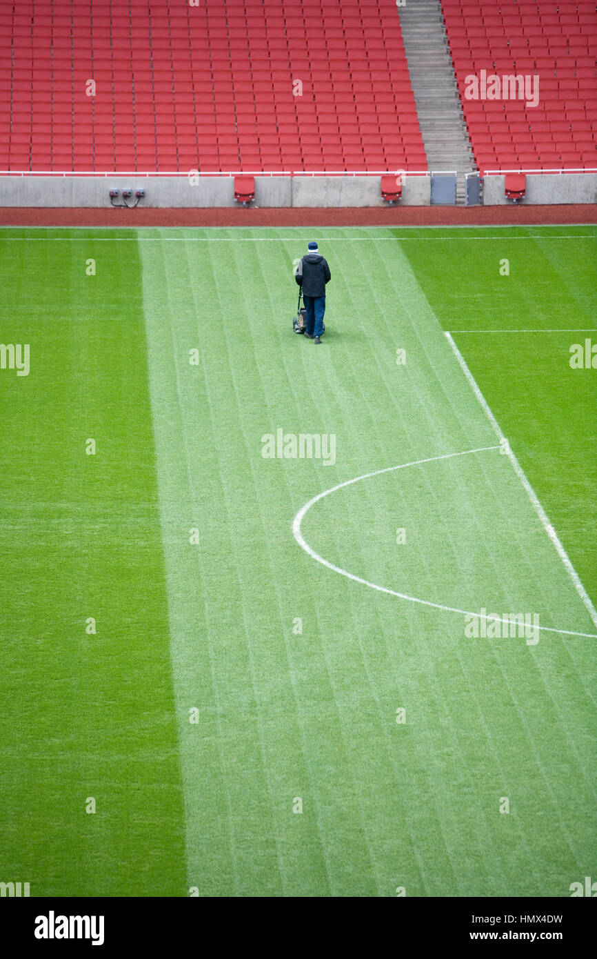 Groundsman solitaire coupe l'herbe sur un grand terrain de football. Banque D'Images