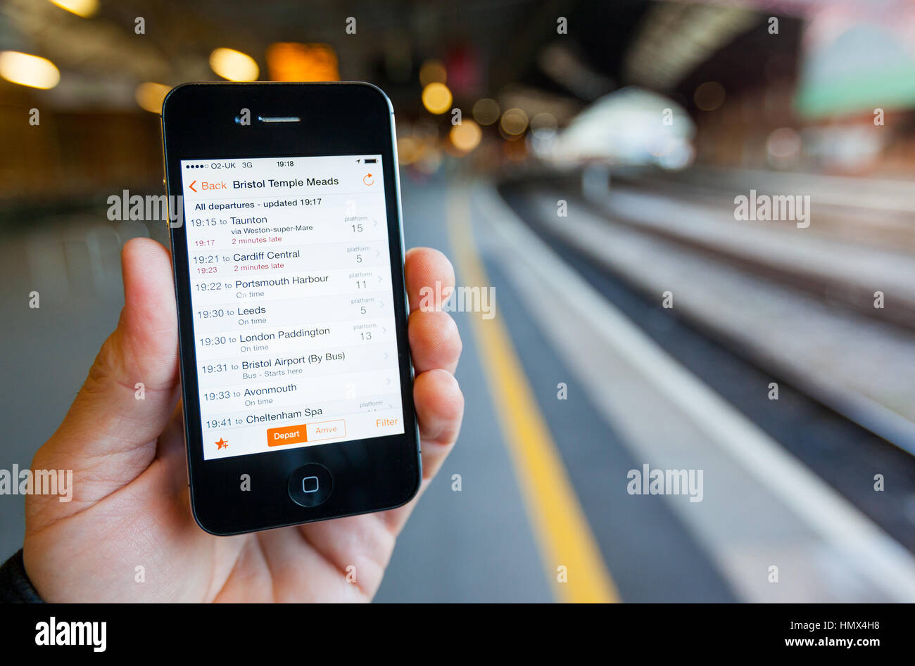 BRISTOL, UK - 8 avril 2014 : un mâle main tenant un iPhone 4s à la gare de Bristol Temple Meads. Le téléphone intelligent affiche en train voyage d'info Banque D'Images